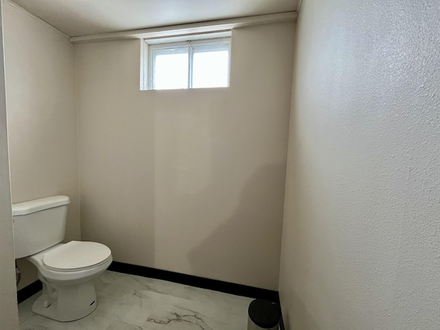 bathroom featuring baseboards and toilet