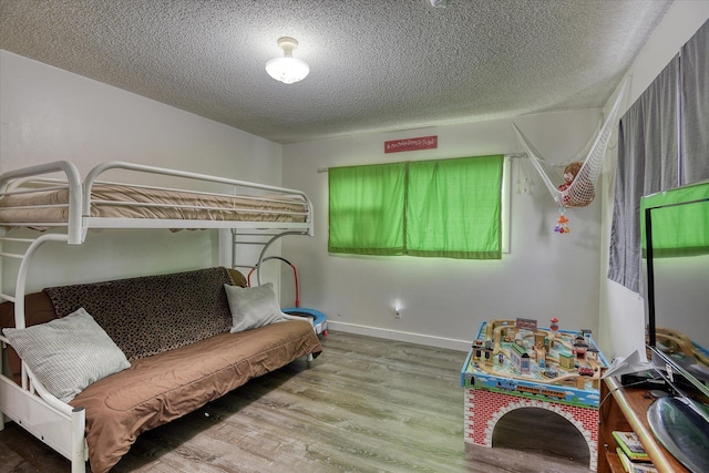 bedroom with a textured ceiling, baseboards, and wood finished floors