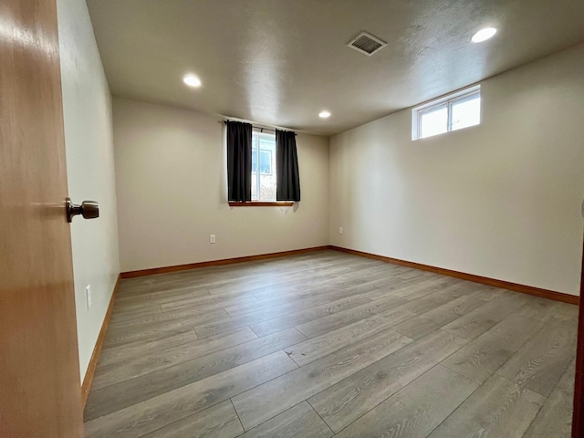 empty room with light wood-style flooring, visible vents, baseboards, and recessed lighting