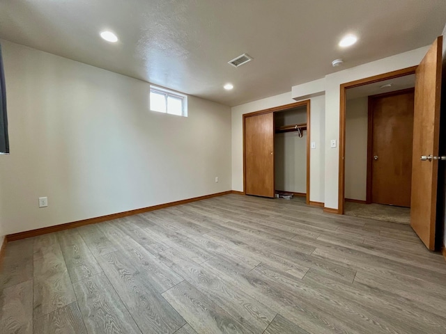 unfurnished bedroom featuring a closet, visible vents, light wood-style flooring, and baseboards