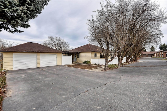 ranch-style home with a detached garage and fence