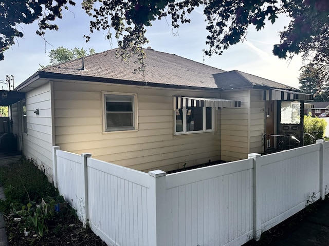 view of home's exterior featuring a fenced front yard and a shingled roof