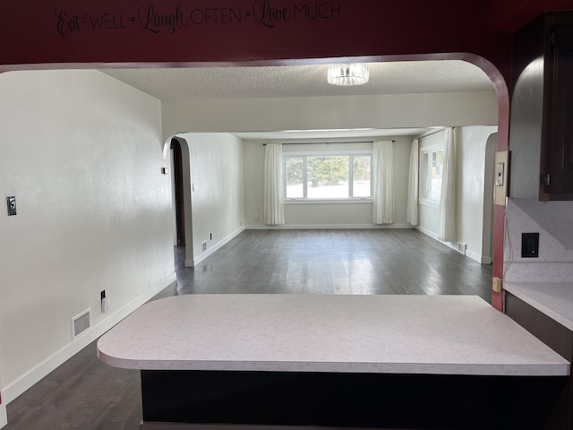 interior space featuring arched walkways, light countertops, a textured ceiling, and visible vents