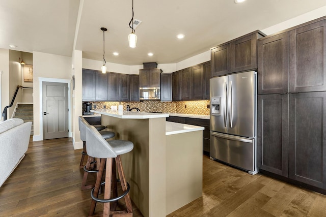 kitchen featuring light countertops, hanging light fixtures, appliances with stainless steel finishes, a kitchen island, and dark brown cabinets