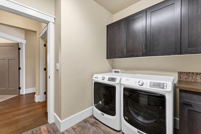 washroom featuring cabinet space, dark wood finished floors, washer and clothes dryer, and baseboards