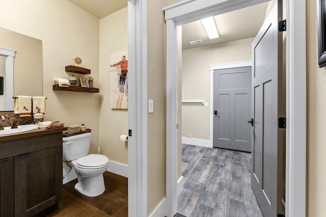 bathroom featuring toilet, vanity, wood finished floors, and visible vents