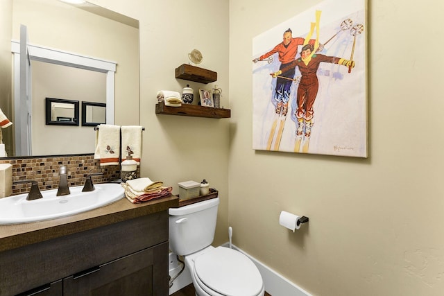 bathroom with toilet, vanity, and decorative backsplash