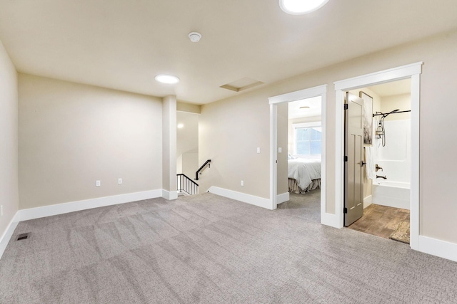 interior space with baseboards, attic access, and light colored carpet