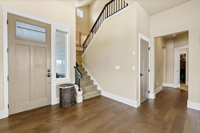 foyer with dark wood-style floors, stairs, a high ceiling, and baseboards