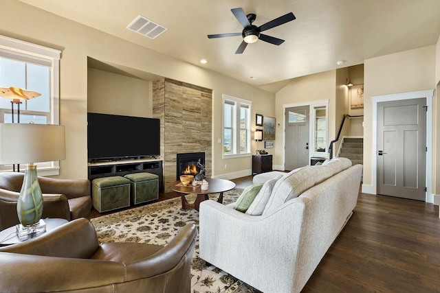 living area with baseboards, visible vents, a tiled fireplace, dark wood-type flooring, and stairs