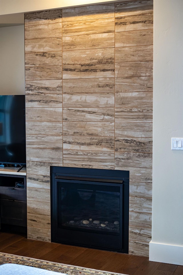 room details featuring a large fireplace and wood finished floors