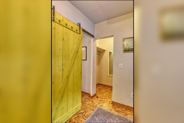 hallway with a barn door and baseboards