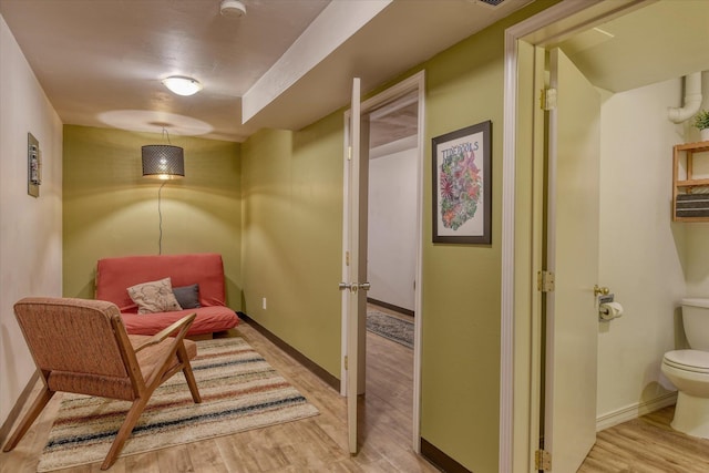 sitting room with baseboards and light wood-style floors