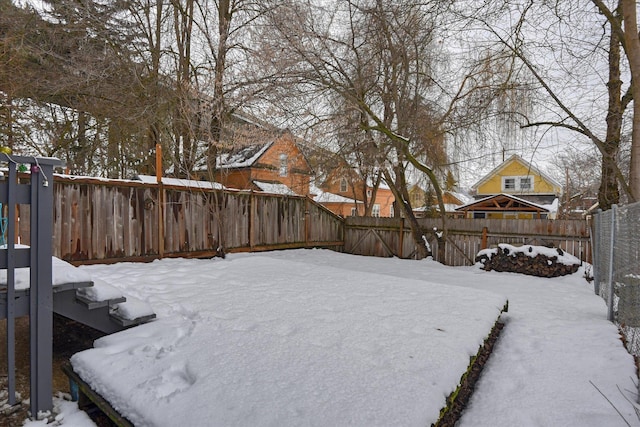 yard layered in snow featuring a fenced backyard