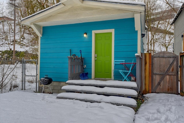 snow covered property entrance with a gate and fence