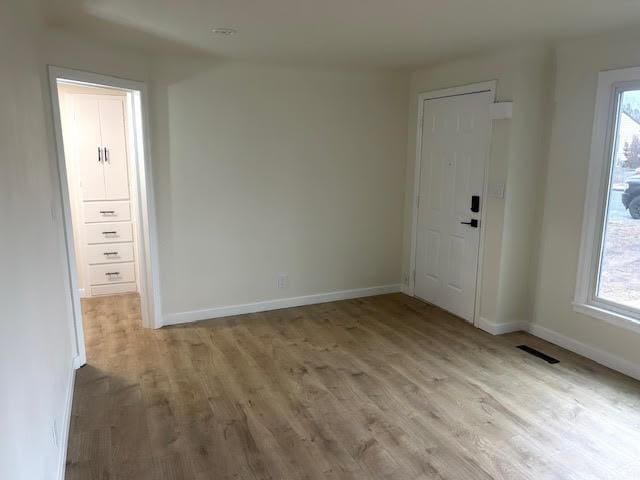 unfurnished room with light wood-type flooring, plenty of natural light, and baseboards