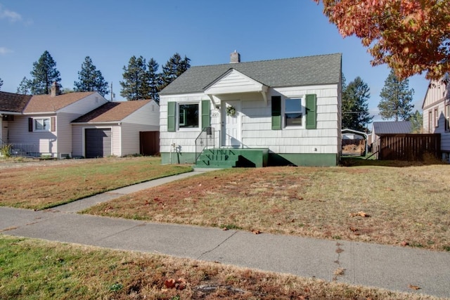 bungalow-style house with a garage, a shingled roof, a chimney, and a front lawn