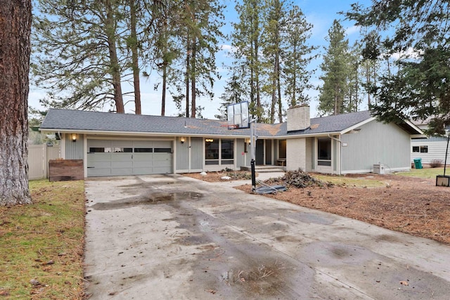 ranch-style house featuring a garage, driveway, a chimney, fence, and brick siding