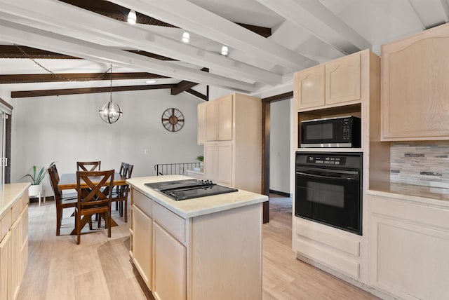 kitchen with light wood finished floors, a kitchen island, decorative light fixtures, light countertops, and black appliances