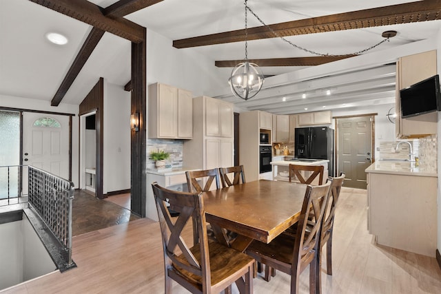 dining space featuring baseboards, lofted ceiling with beams, light wood finished floors, and an inviting chandelier