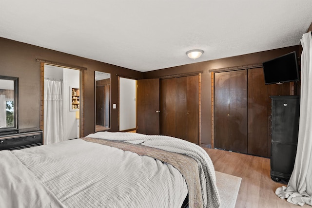 bedroom featuring light wood-style flooring and two closets