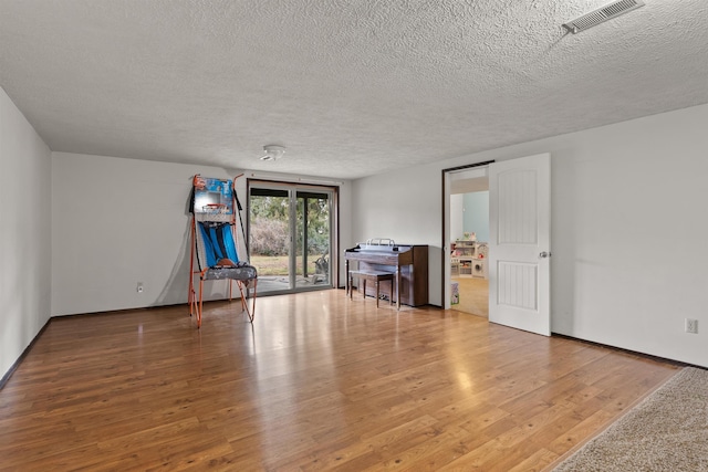 unfurnished room featuring a textured ceiling, visible vents, and wood finished floors