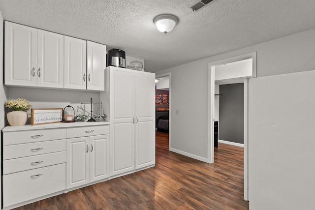 kitchen with visible vents, light countertops, dark wood-type flooring, and white cabinetry