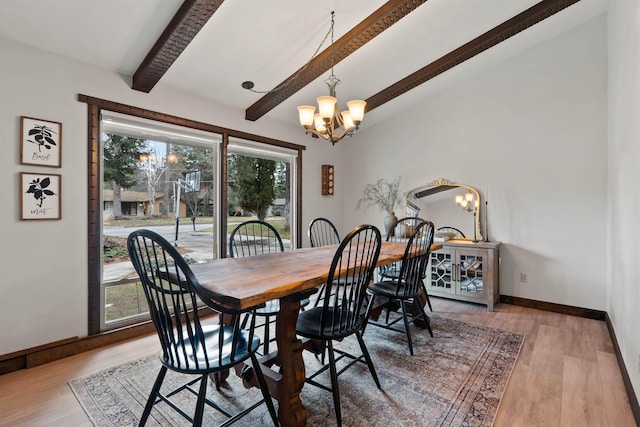 dining area with a chandelier, light wood-type flooring, lofted ceiling with beams, and baseboards