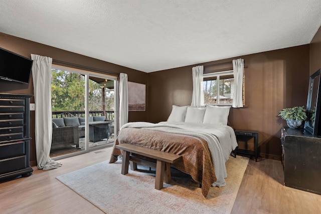 bedroom with a textured ceiling, access to outside, and light wood-type flooring