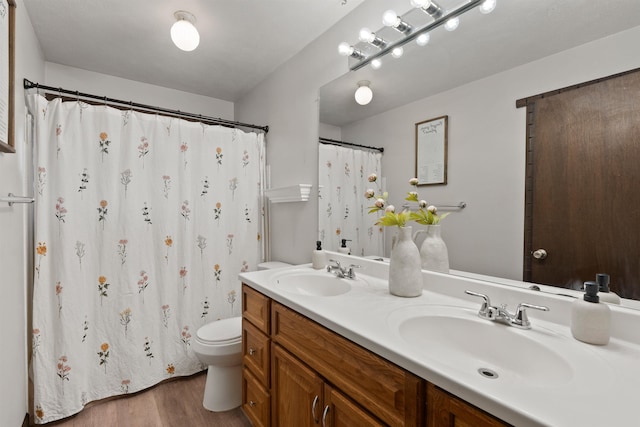 bathroom featuring wood finished floors, a sink, toilet, and double vanity