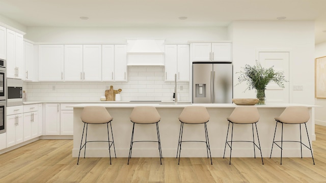 kitchen with stainless steel appliances, white cabinetry, light countertops, custom exhaust hood, and an island with sink