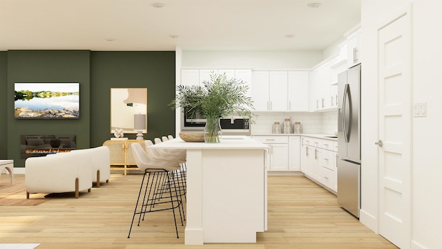 kitchen with a kitchen island, a kitchen breakfast bar, light countertops, light wood-type flooring, and white cabinetry