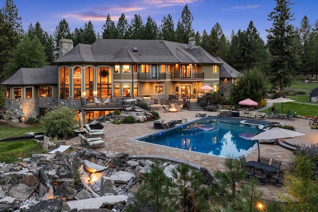 rear view of house featuring a fire pit, a patio, a chimney, and an outdoor pool