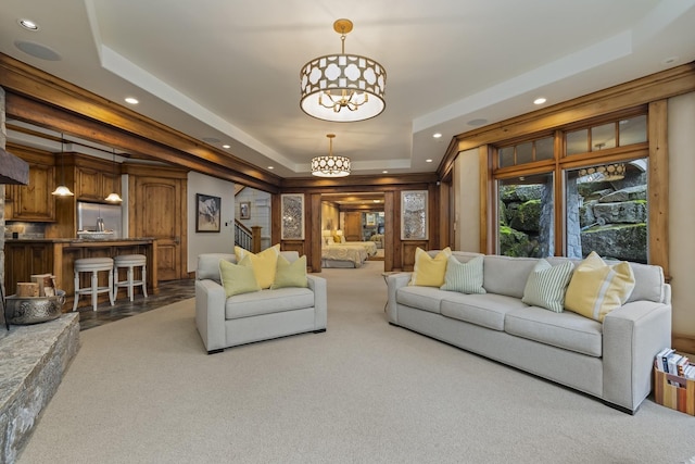 living area featuring stairs, a tray ceiling, recessed lighting, and an inviting chandelier