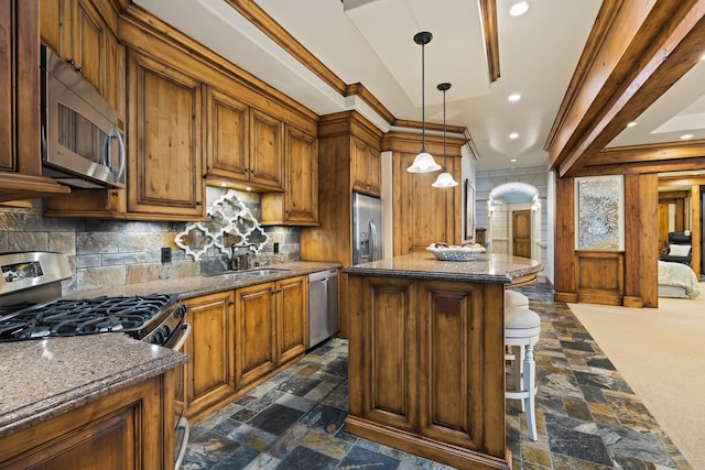 kitchen with arched walkways, stainless steel appliances, stone tile flooring, a kitchen island, and a sink