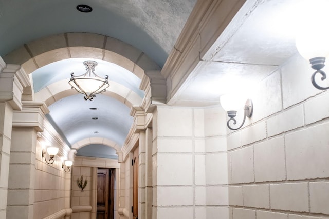 corridor featuring concrete block wall and lofted ceiling