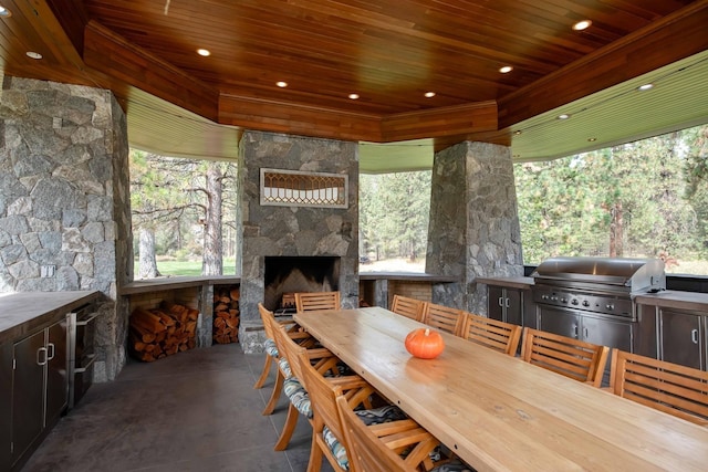 view of patio with exterior kitchen, outdoor dining space, an outdoor stone fireplace, and area for grilling