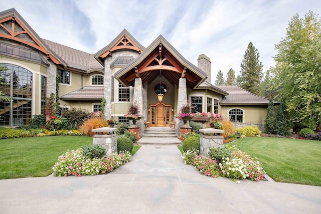 view of front of home featuring a front yard, a chimney, and stucco siding