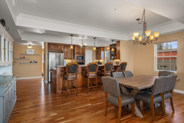 dining area featuring a raised ceiling, crown molding, an inviting chandelier, and wood finished floors