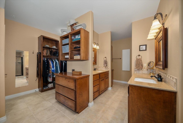 bathroom featuring tile patterned flooring, two vanities, a sink, and a spacious closet