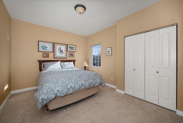 bedroom with a closet, light colored carpet, and baseboards