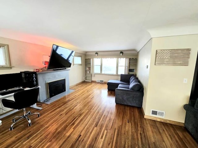 living room with a fireplace with flush hearth, wood finished floors, and visible vents