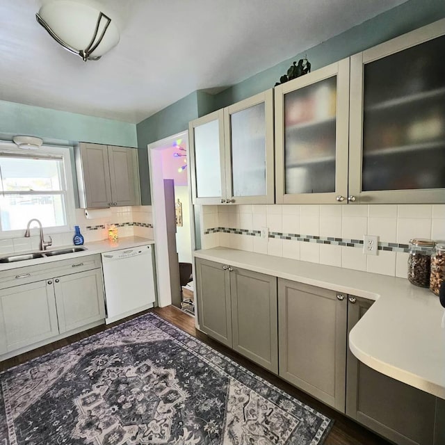 kitchen featuring a sink, white dishwasher, light countertops, gray cabinetry, and backsplash