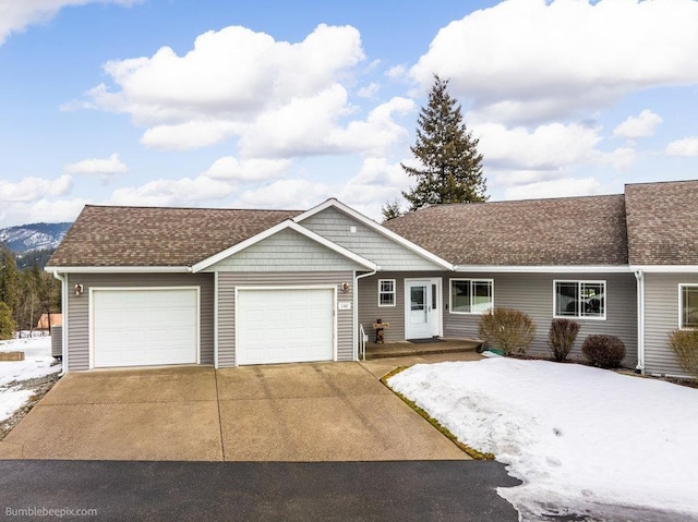 single story home with concrete driveway, roof with shingles, an attached garage, and a mountain view