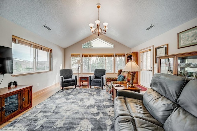 living area featuring vaulted ceiling, a healthy amount of sunlight, a notable chandelier, and light wood-style floors