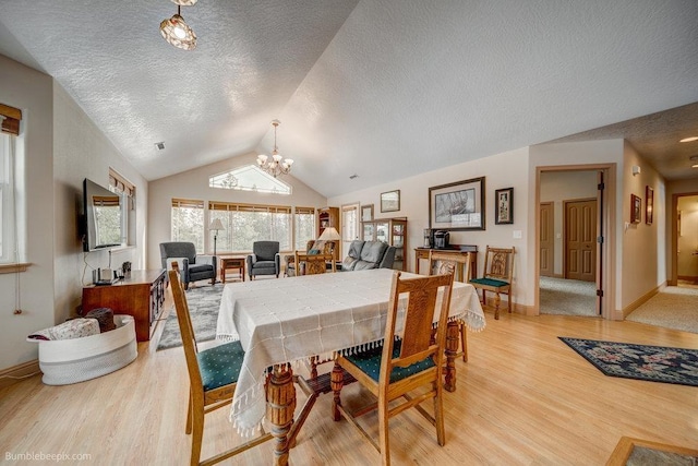 dining area featuring lofted ceiling, a textured ceiling, a notable chandelier, baseboards, and light wood-style floors