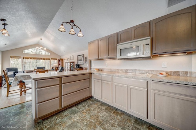 kitchen featuring a peninsula, white microwave, light countertops, and decorative light fixtures