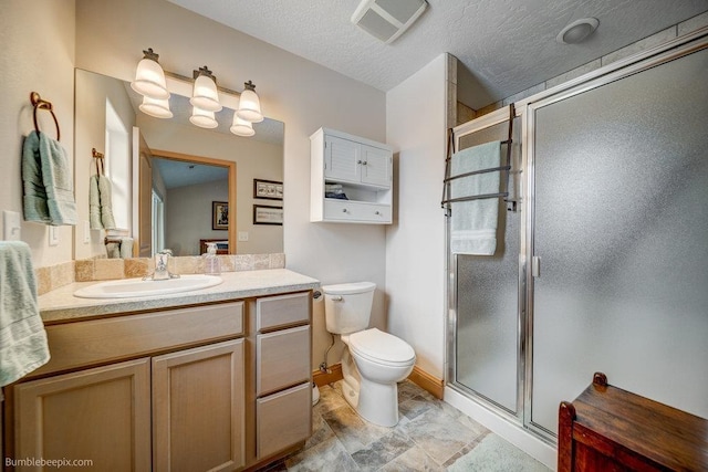 bathroom featuring visible vents, toilet, a shower stall, vanity, and a textured ceiling