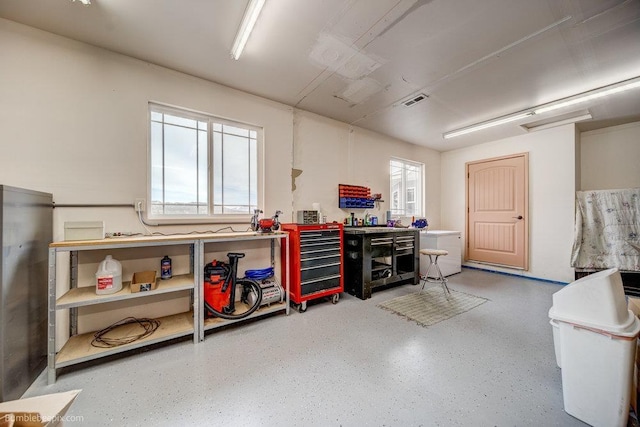 interior space featuring a wealth of natural light, speckled floor, a workshop area, and visible vents