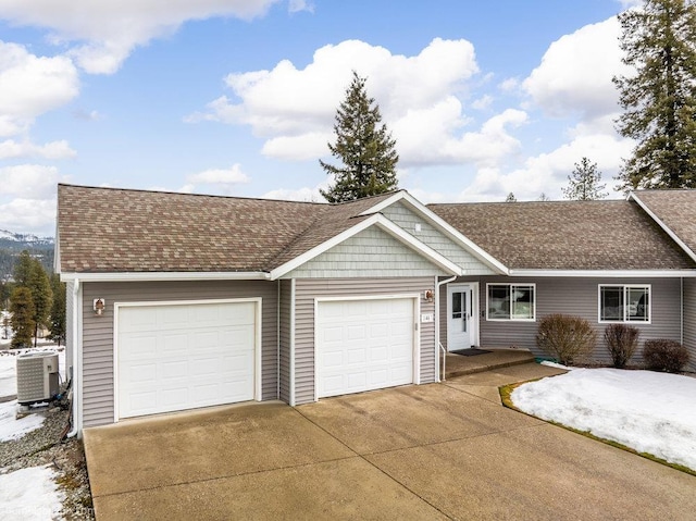 ranch-style home with driveway, roof with shingles, an attached garage, and central air condition unit